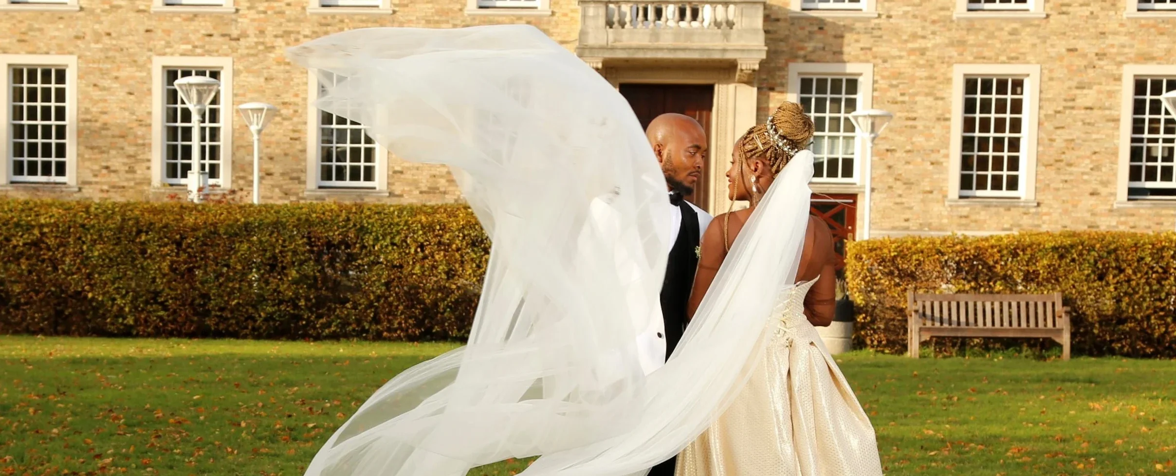 Wale and Shekemi sharing a romantic wedding portrait with a flowing bridal veil at a luxury wedding venue in the UK