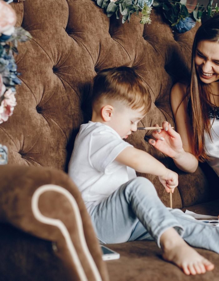 Mother with son sitting on a brown chair. Little boy drawing.